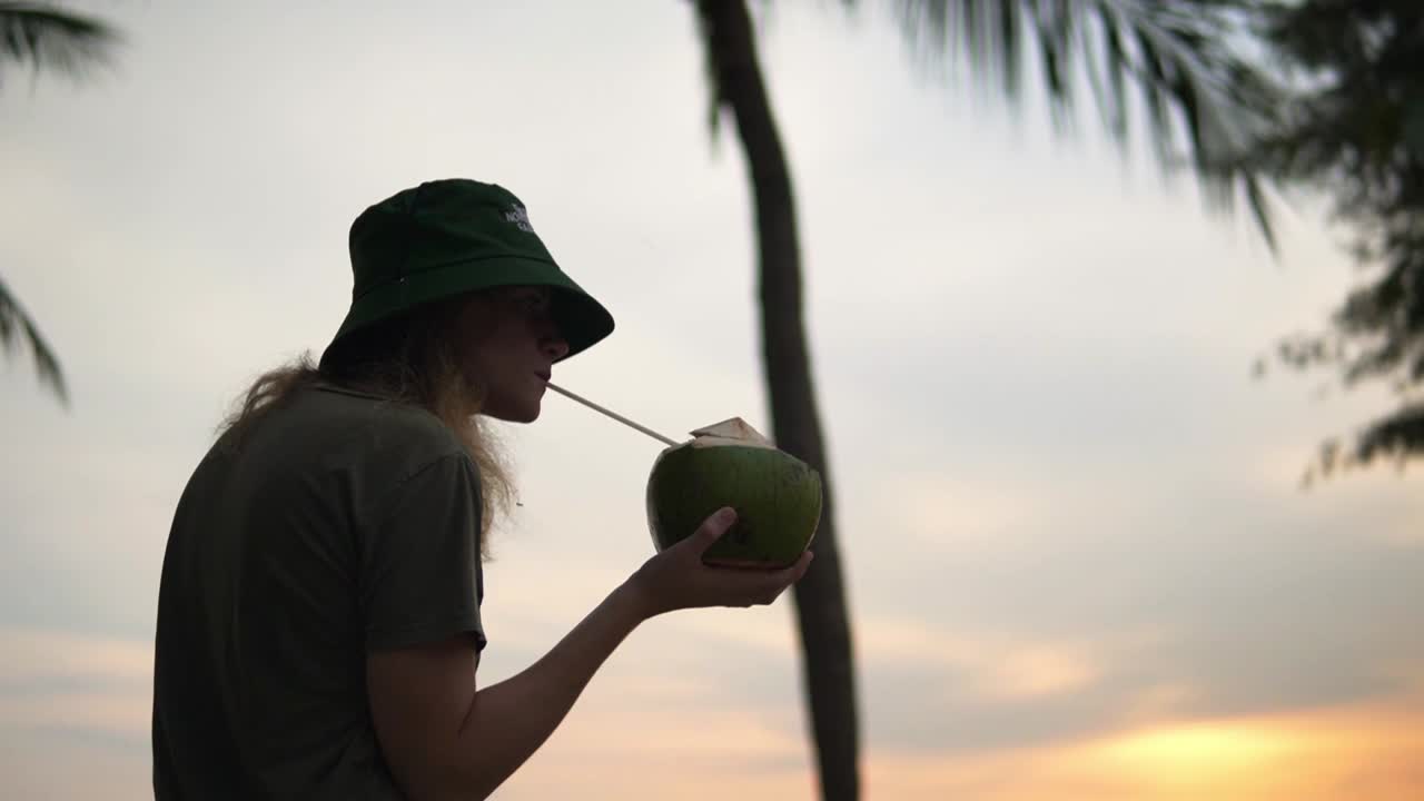 mujeres disfrutando de un coco fresco en una playa bajo algunas palmeras, tiro de bajo ángulo