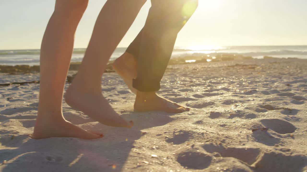 sección baja de una pareja caminando en la playa en un día soleado 4k