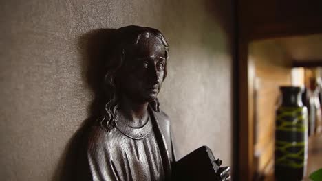 close up view of small indoor statue of jesus christ holding the bible in relgious home