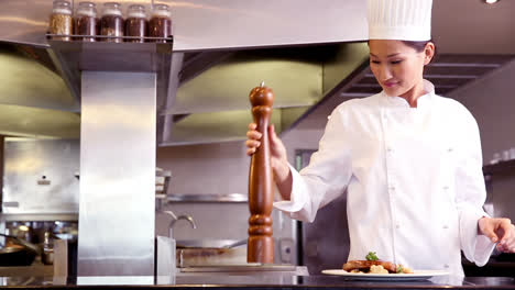 chef grinding pepper over beef dish