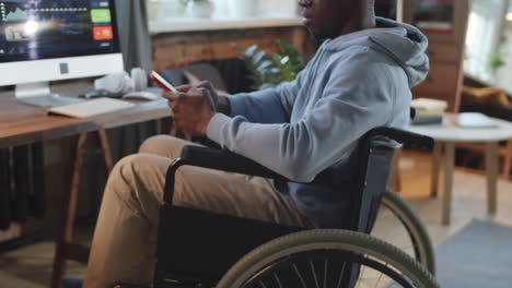 man in wheelchair working on computer and phone