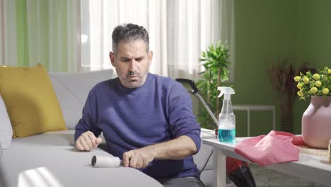 hombre maduro limpiando con colector de polvo en el sofá en casa quejándose de la suciedad.