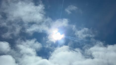 pilot pov fpv flying under a layer of thin clouds with a veiled shining sun in a deep blue sky. 4k 60fps