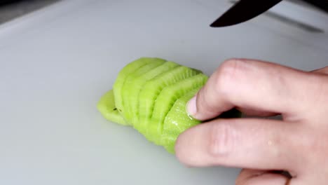 womans hands cutting kiwi on a chopping board