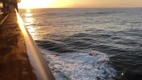 rolling, splashing water off the right, starboard side of a cruise ship, forward view, toward the setting sun