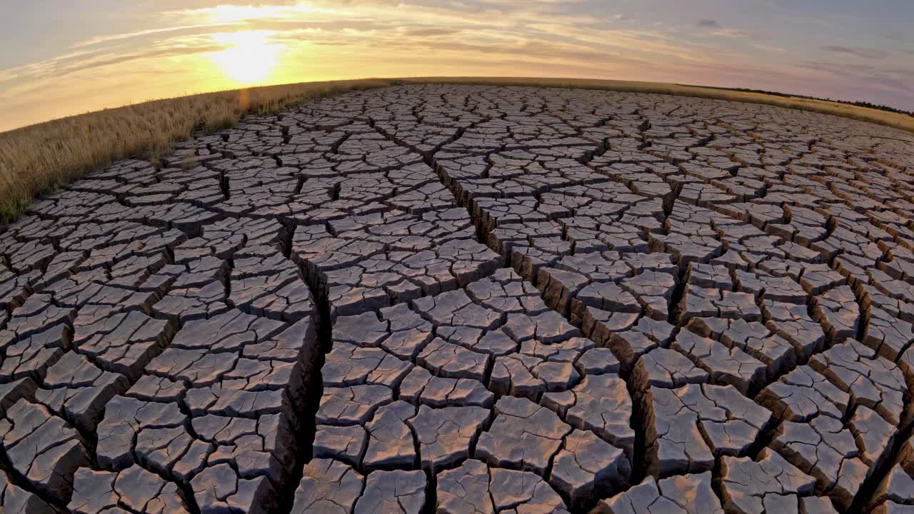 Aerial view of cracked, dry earth at sunset, highlighting environmental themes