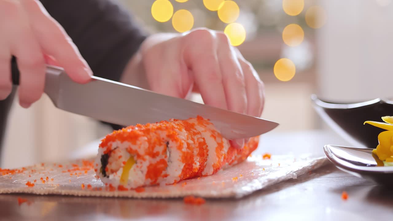 hacer sushi en la cocina de casa. manos de mujer enrollando sushi casero.