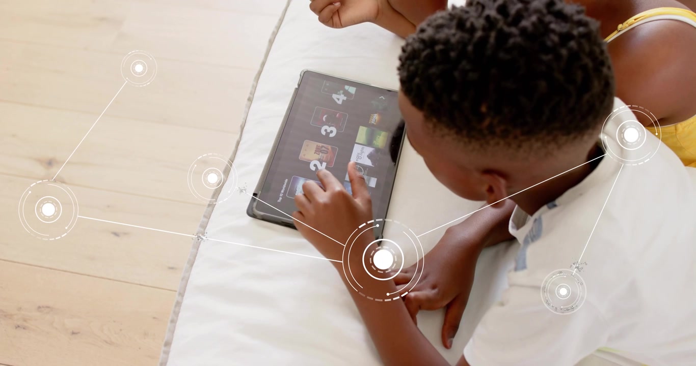 Boy lying on floor swiping tablet popping up nodes and navigating tech gallery as sister observing