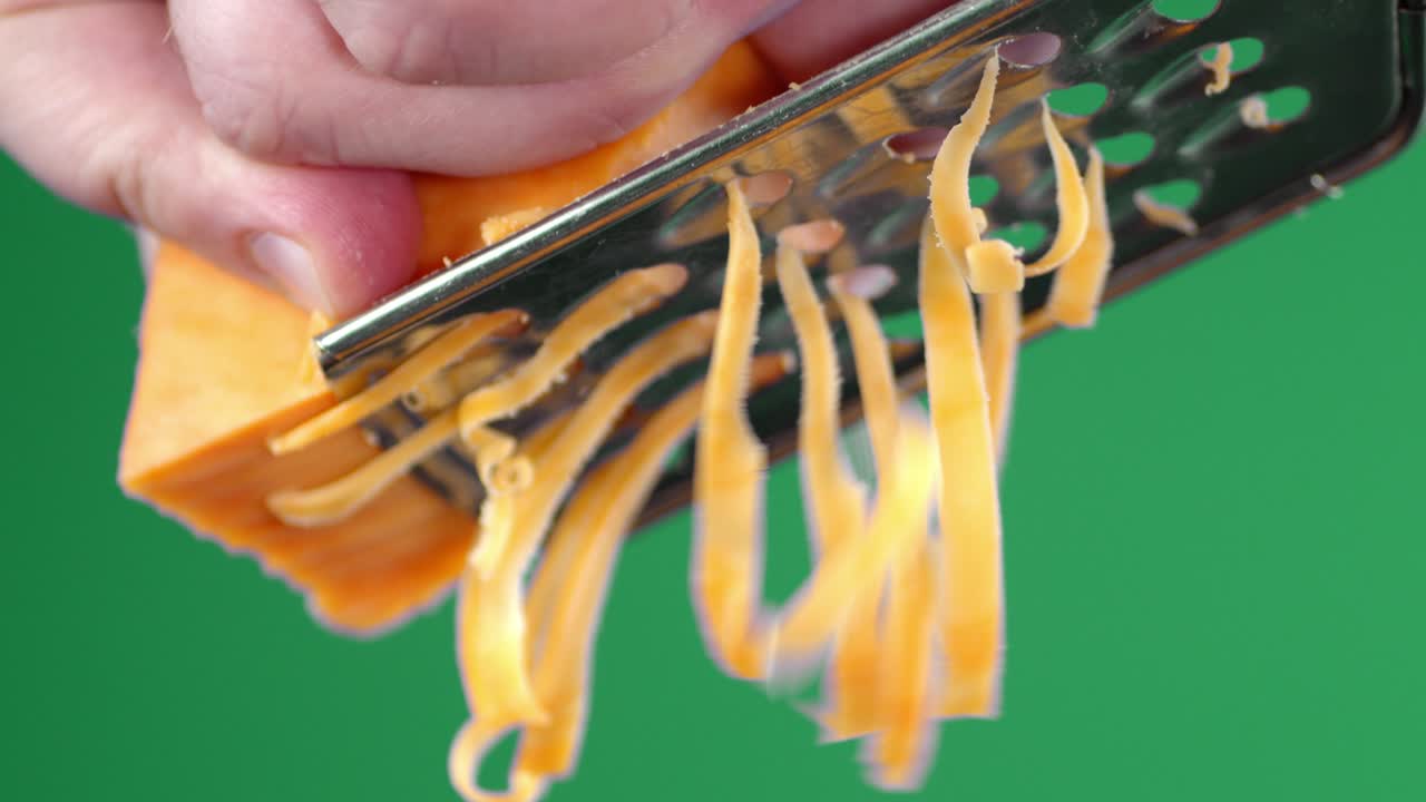 Male hand rubbed cheddar cheese on a grater.