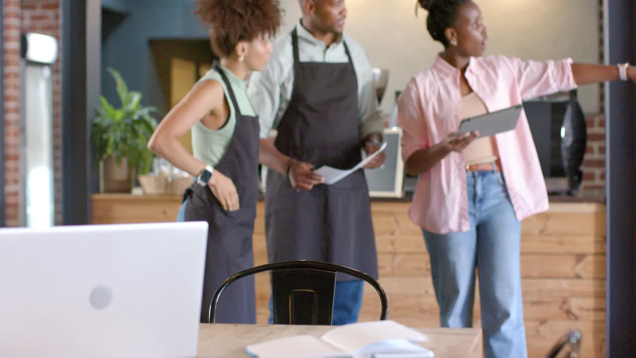 Dopo la messa a fuoco del tavolo, baristi afroamericani che si muovono, controllano il foglio, pianificano tramite tablet in un bar