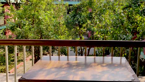 wooden table placed in a balcony with green trees and plants in thr foreground