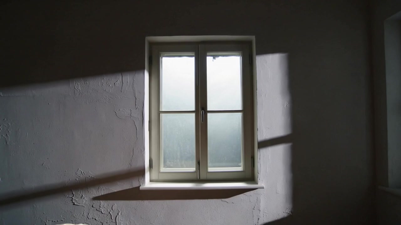 Shifting sunlight moving light cloth behind centered window, changing shadow band on plaster wall