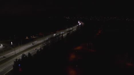 cars driving at night on illuminated highway