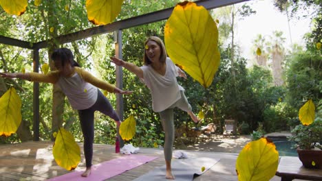 multiple leaves icon falling against two asian women performing yoga