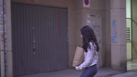 woman walking down city street with a paper bag