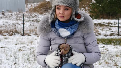 mujer preocupada cuidando de un perro pequeño durante el invierno