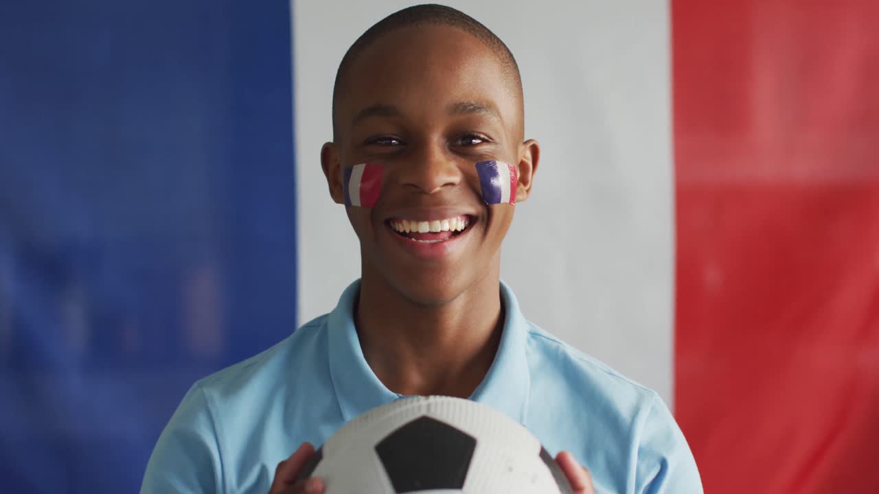 Video of happy african american boy with flag of france holding soccer ball