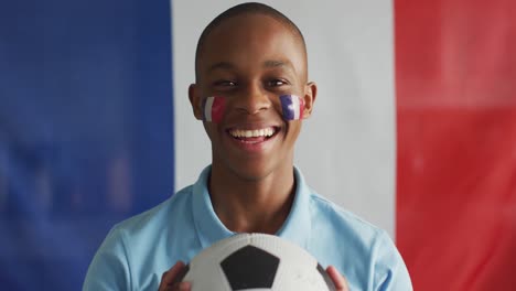 video of happy african american boy with flag of france holding soccer ball