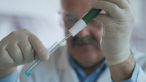 Technician-carefully-drips-the-solution-from-the-pipette-into-glass-tubes-for-DNA-analysis.-Doctor-Drips-Blue-Solution-Into-Glass-Tube-Coronavirus-Pandemic-Hands-Closeup.-High-quality-4k-footage