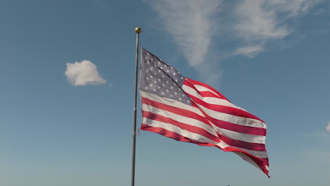 Patriotische-Zeitlupenaufnahme-Einer-Amerikanischen-Flagge,-Die-Im-Wind-Vor-Blauem-Himmel-Weht