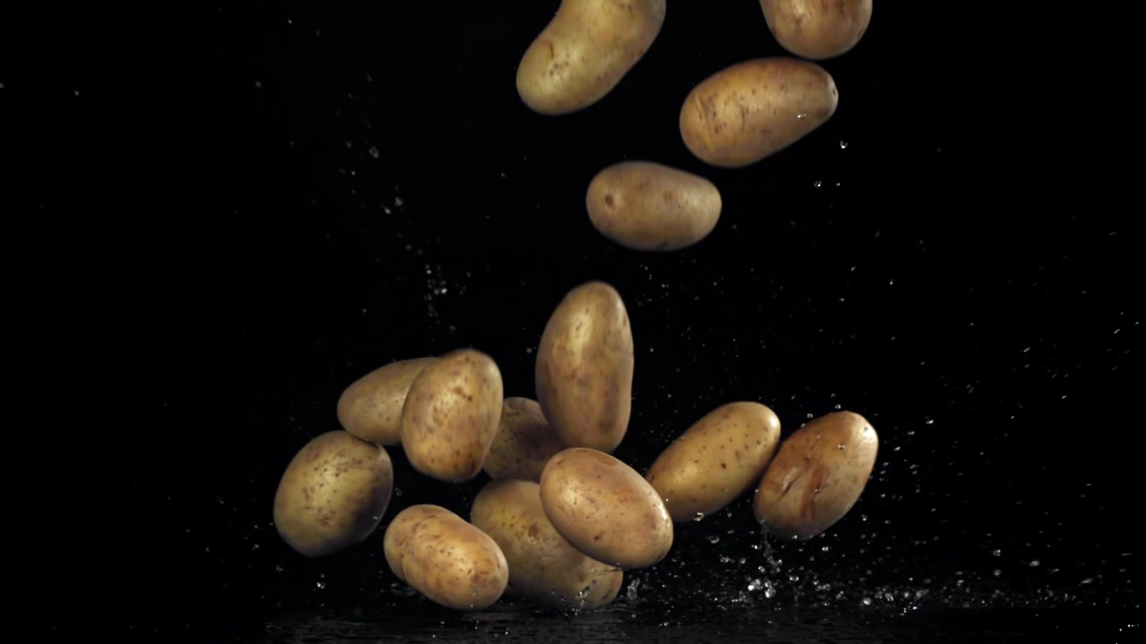 Patate fresche che cadono e schizzano acqua su sfondo nero