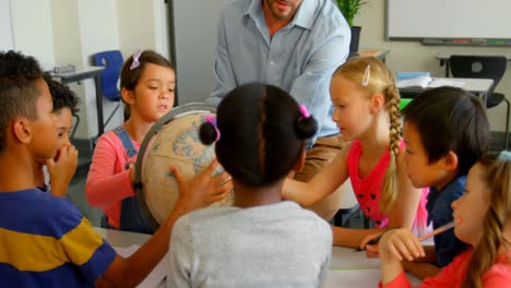 caucasian male teacher teaching his kids about globe in classroom 4k