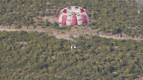 Parachute-with-couple-parasailing-over-woods