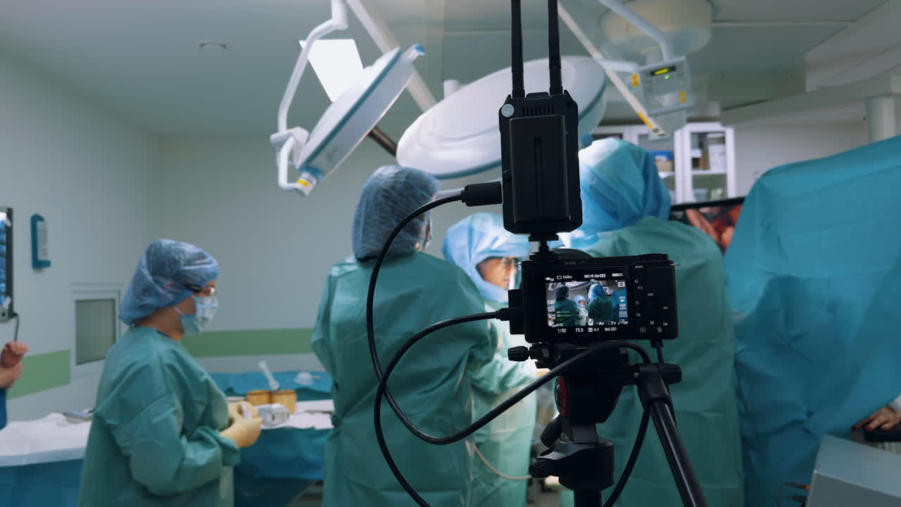 Kyiv, Ukraine, 2 August 2025: Digital camera setup filming a surgical team at work under bright ceiling lights. The image shows the doctors performing an intervention while the video equipment records the entire scene