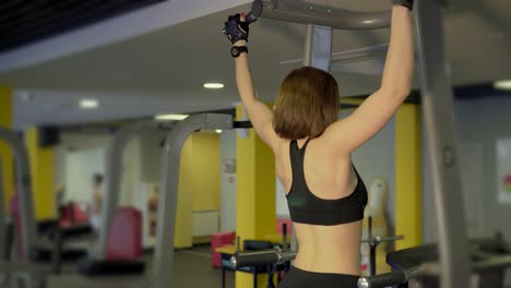 woman doing pull-ups in gym