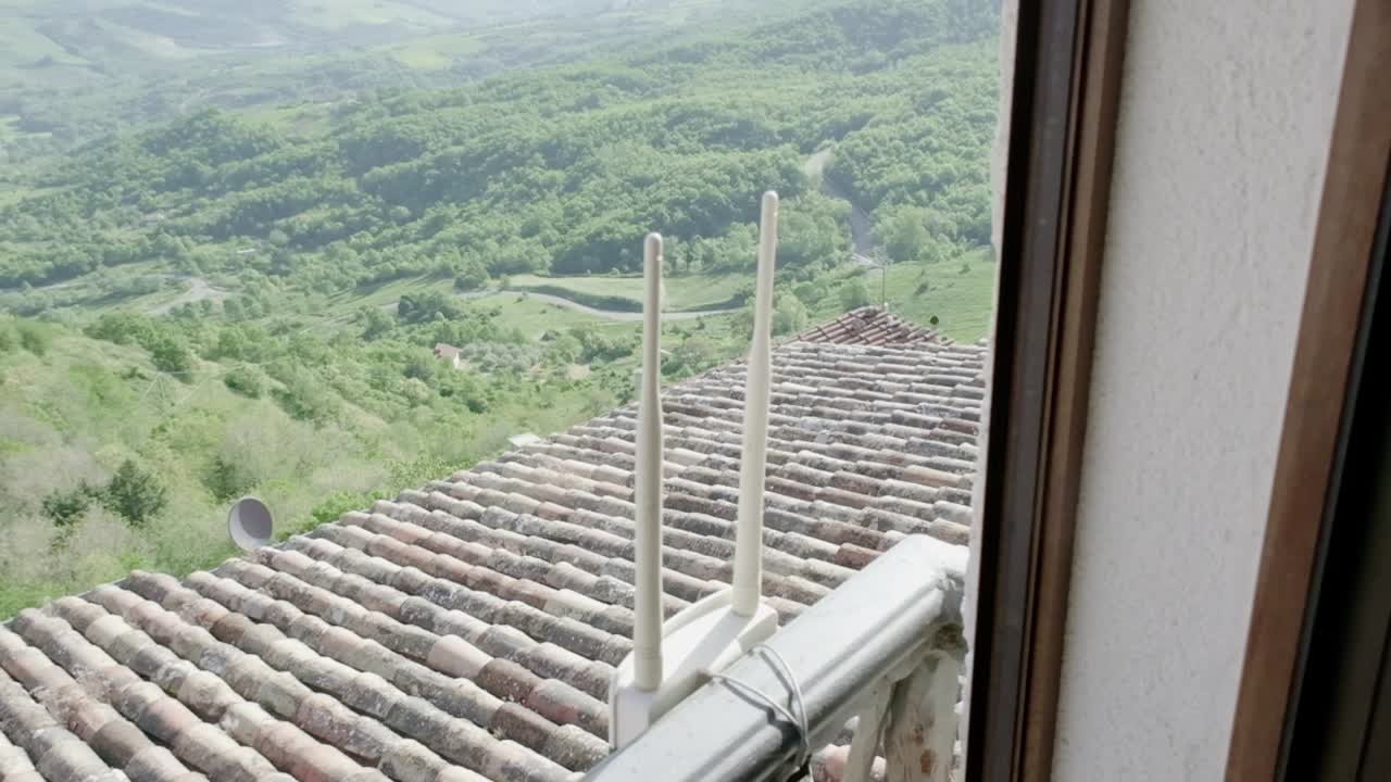 un extensor de señal wifi montado en el exterior de una ventana, rodeado por un campo tranquilo
