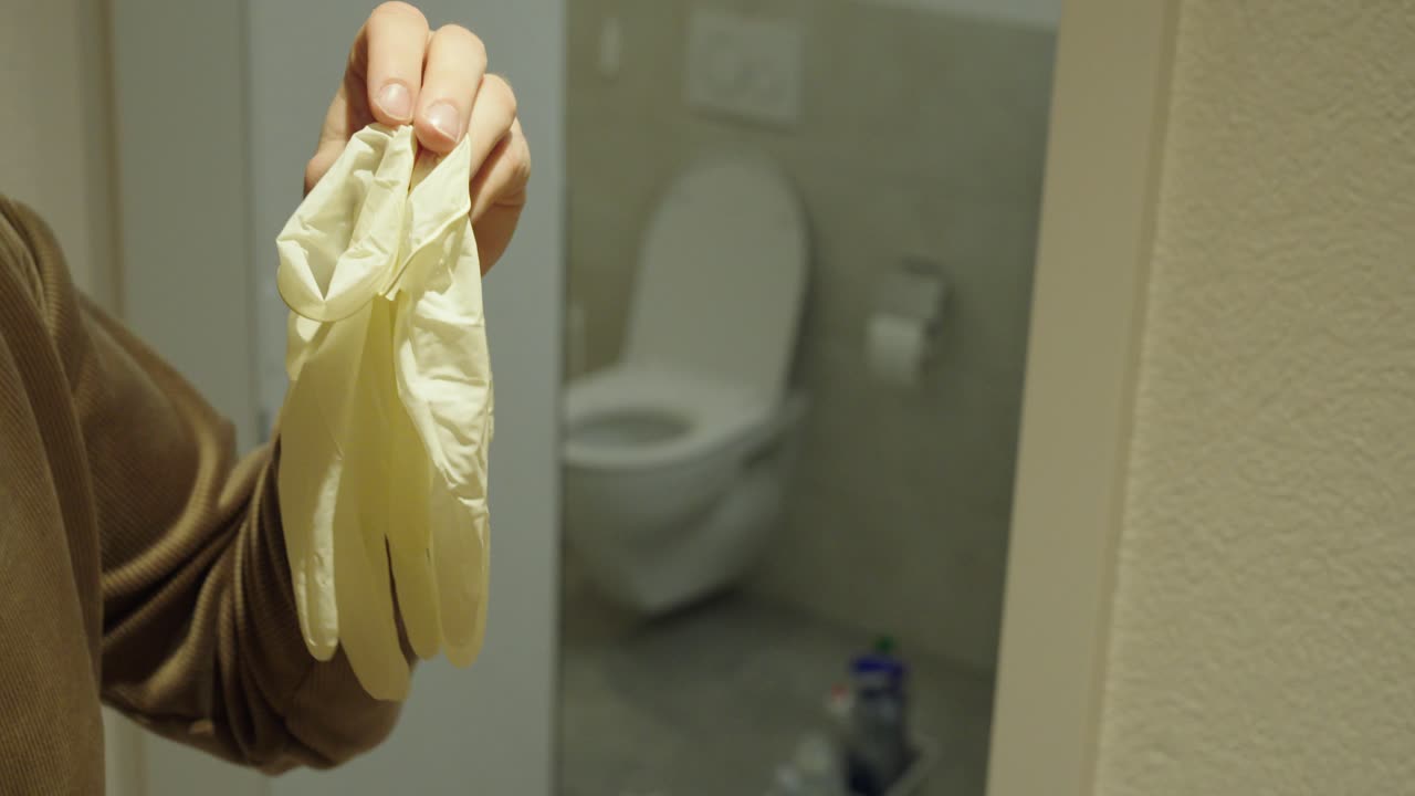 Close-up of a person correctly removing disposable gloves in a bathroom. Concept of hygiene procedure, contamination prevention, infection control, and health safety