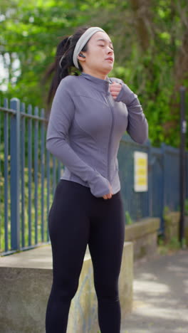 vertical video of young woman zipping up sportswear top before exercising running along urban street