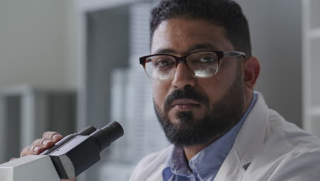 portrait of scientist with microscope during research in laboratory