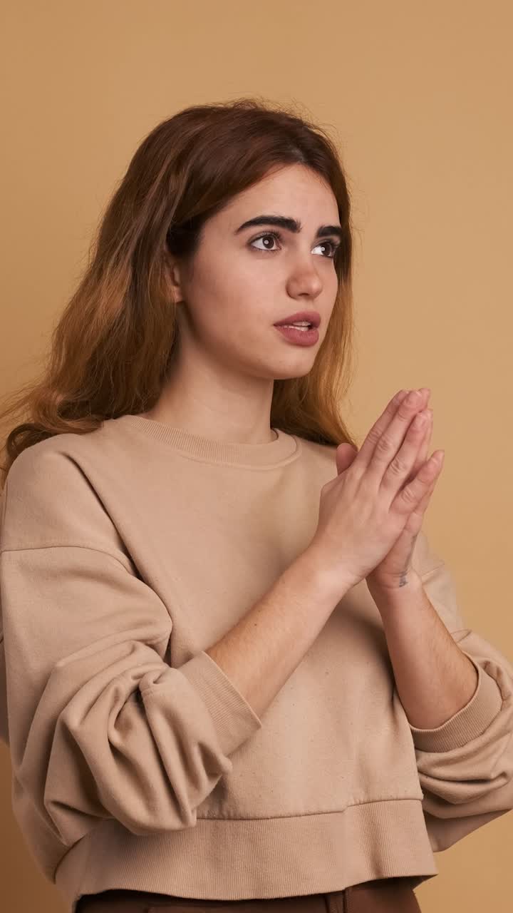 Young woman saying prayers with folded hands. Vertical Footage