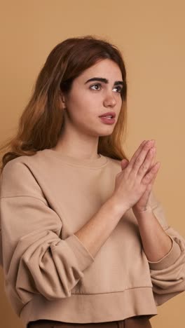 young woman saying prayers with folded hands. vertical footage