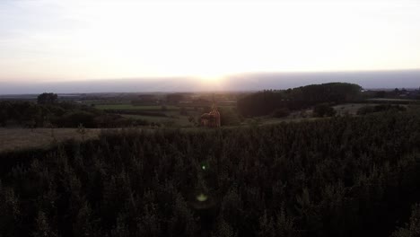 A-drone-shot-flying-to-the-front,-seeing-a-see-through-church,-with-a-sunset-behind-it