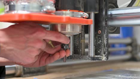 primer plano de las manos instalando una broca en un enrutador cnc
