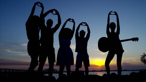 silhouette of people making heart symbol with hand