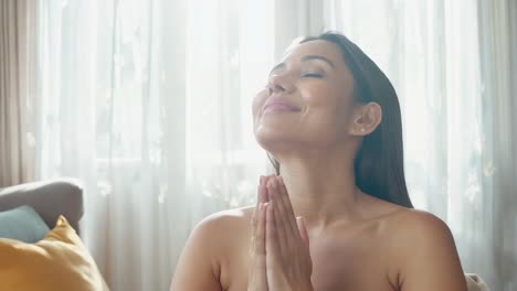 mulher orando com os olhos fechados e sorrindo