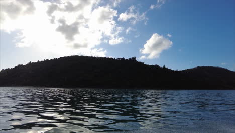 POV side of the boat moving past a silhouetted tropical island in the Whitsundays, QLD, Australia