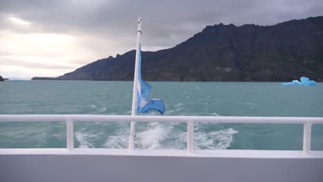 shot of argentine flag in argentino lake moving on a boat