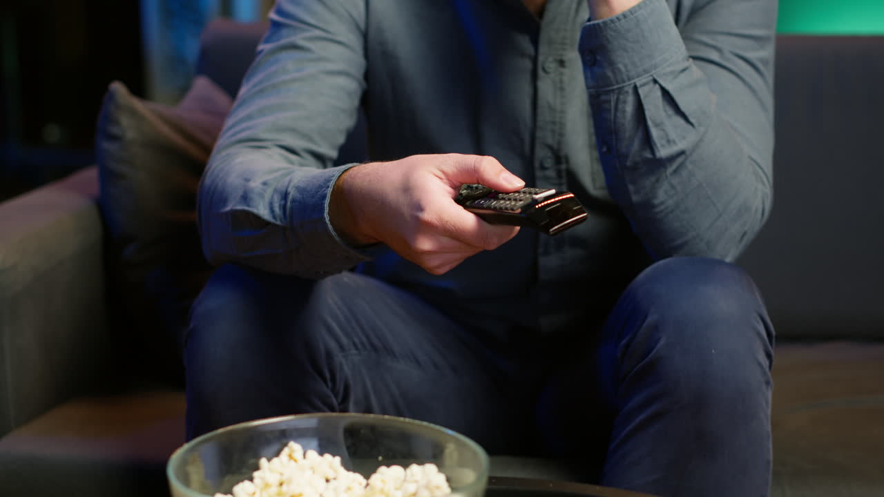 primer plano de un hombre en el sofá usando el control remoto