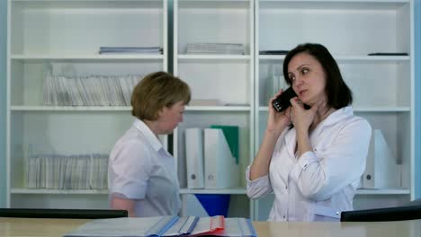 smiling female nurse answering phone at the hospital reception desk