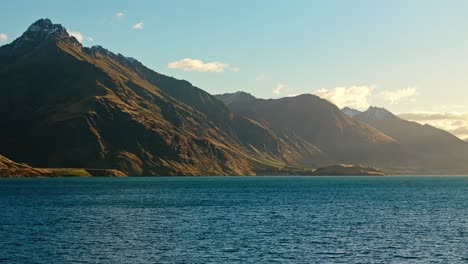 un suave resplandor de luz se extiende por las empinadas laderas de las colinas por encima del lago wakatipu
