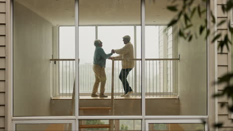 una pareja de ancianos bailando en su casa.