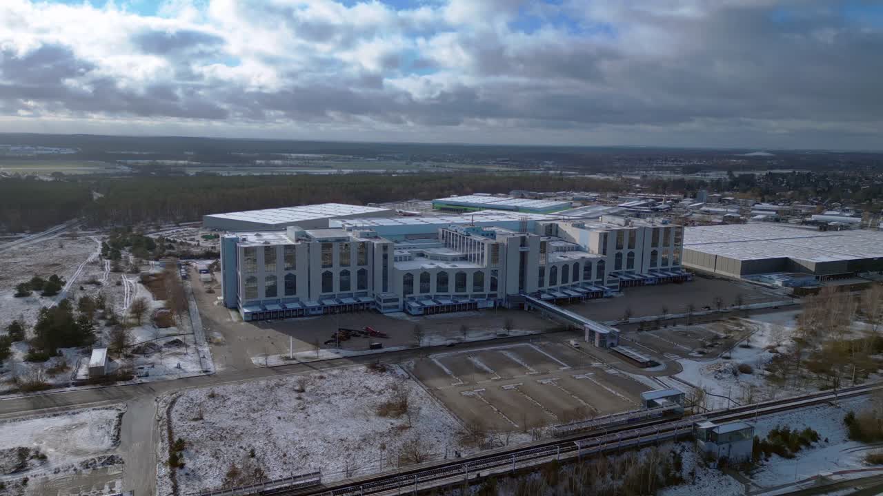 Large distribution center with loading docks and parking lot under a cloudy sky in winter. Beautiful aerial view flight fly reverse drone