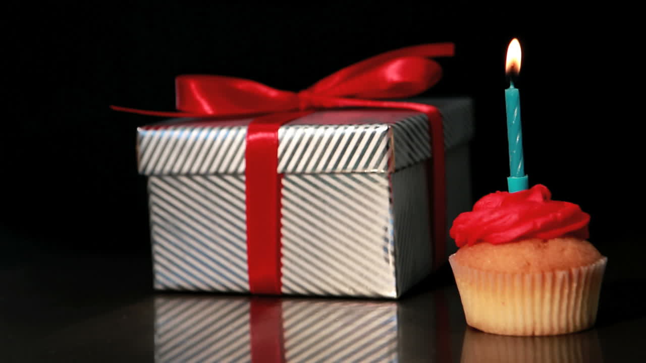 Vela apagada en cupcake junto a un regalo
