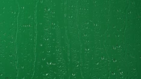 lluvia de agua, gotas de lluvia que caen en el vidrio de la ventana sobre la pantalla verde de la llave de croma