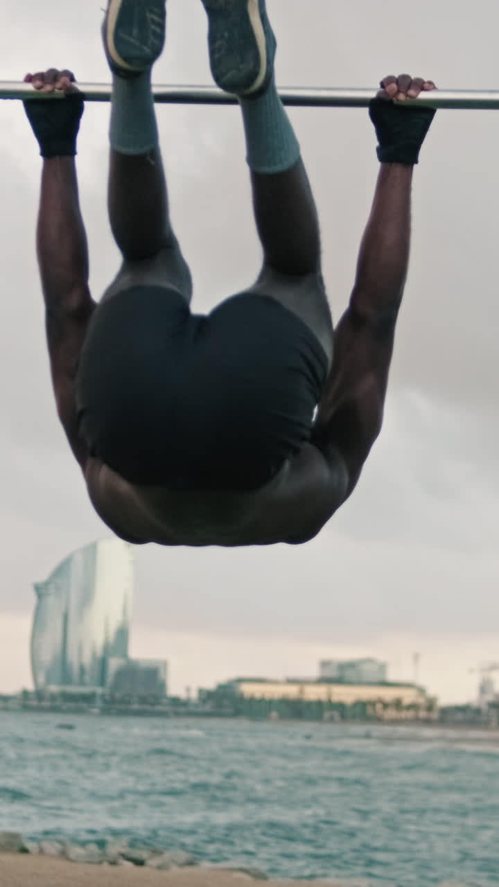 Muscular Man Performing Calisthenics Leg Raises on a Bar Outdoors