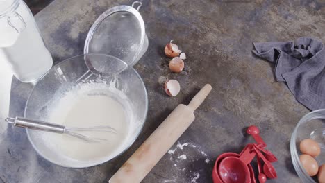 Close-up-of-flour,-milk-and-eggs-on-worktop-in-kitchen,-slow-motion